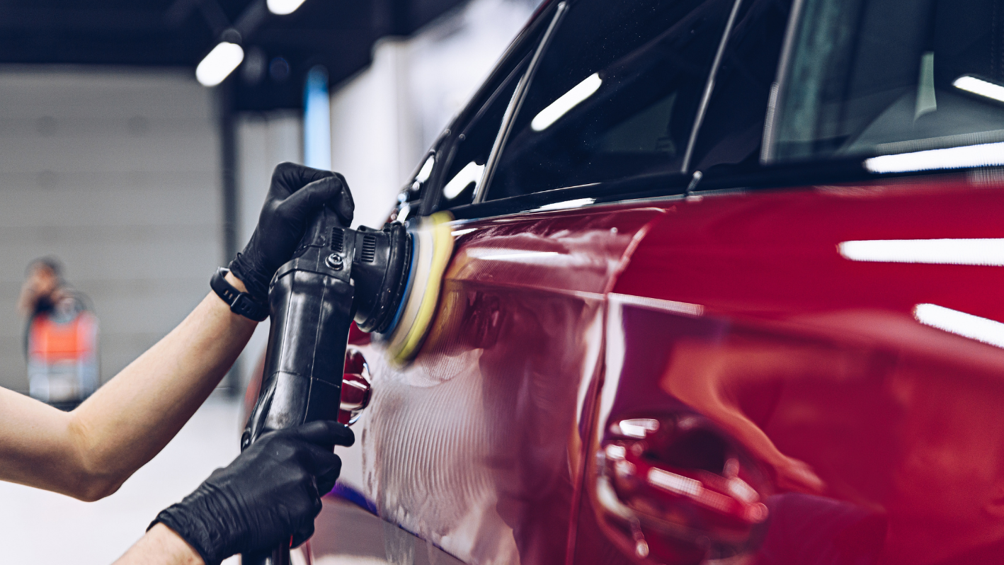 A person polishing a car in a garage