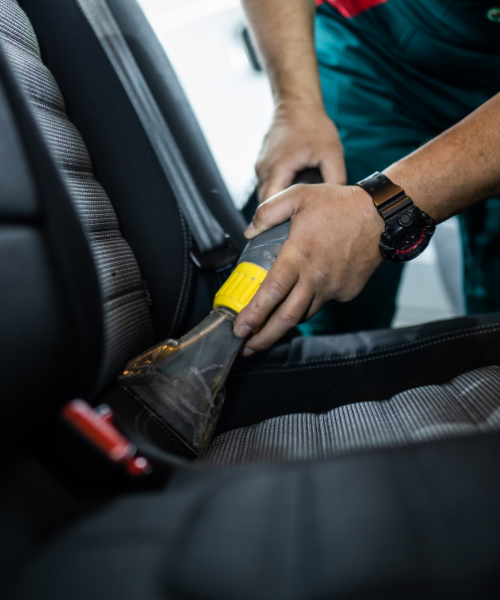 A man cleaning a car seat with a sponge