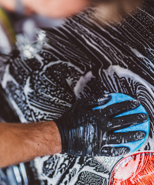 A man waxing a car with a blue glove