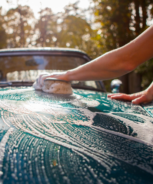 A person washing a car with a sponge